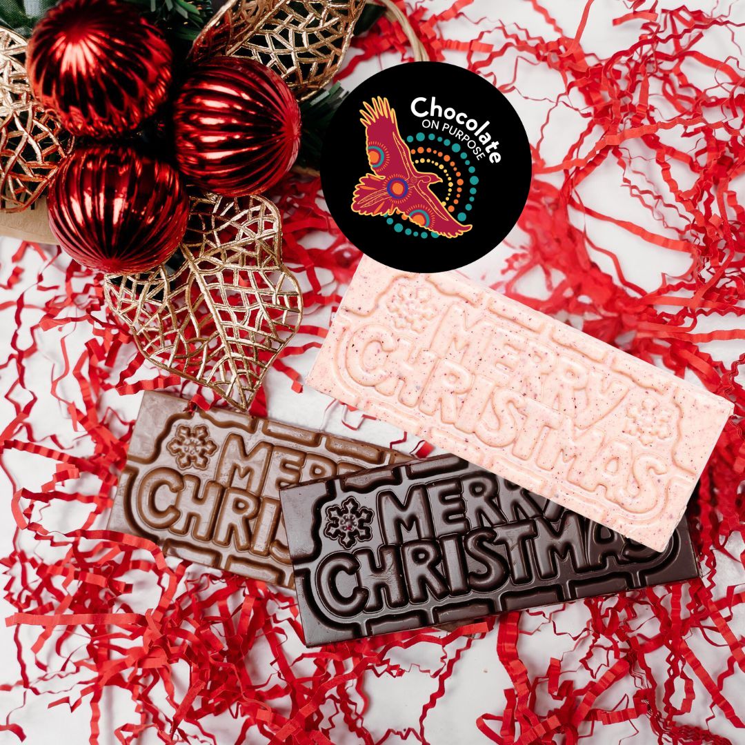 Chocolate On Purpose 'Merry Christmas Gift Hamper Bag' with three chocolate bars, White Chocolate with Ooray (Davidson Plum) and Milk Chocolate with Munthari (Muntrie Berry) and Dark Chocolate with Gulalung (Finger Lime), with red baubles & gold holly leaves with Chocolate On Purpose Logo stamp.
