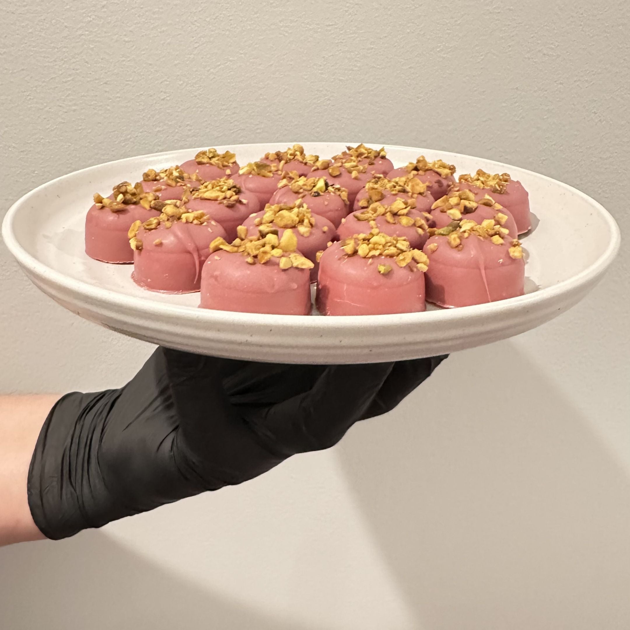 Chocolate On Purpose Ruby Pistachio Truffles with layers of Pashmak (persian ferry floss) and creamy pistachio butter, dipped in pink ruby chocolate, and topped with pistachio, on a white plate. A delicious Valentine’s Day gift idea.