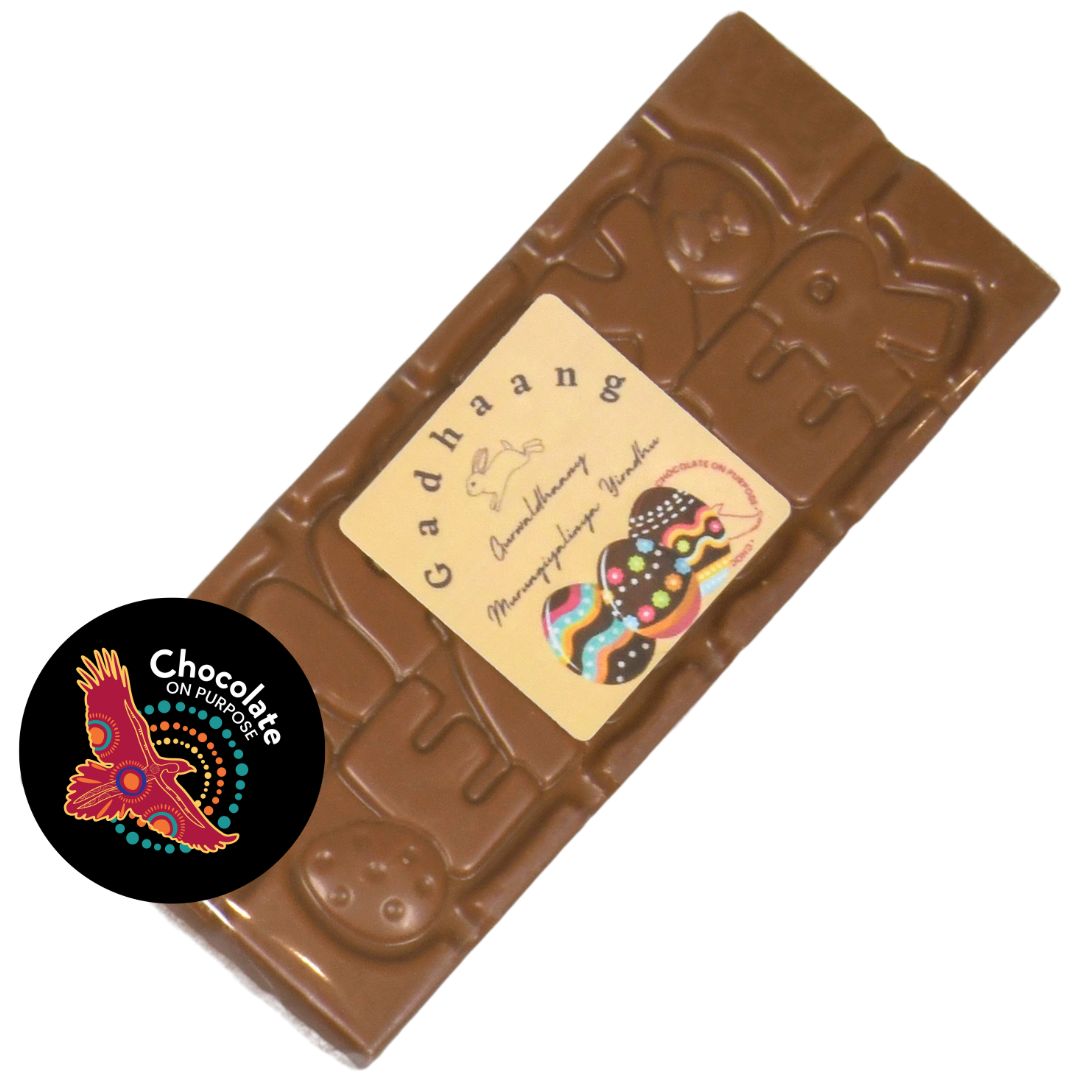 Happy Easter chocolate bar in clear wrapper, creamy white chocolate with native botanical Muntrie Berry and raised “HAPPY EASTER” lettering, with Wiradjuri Easter Greeting on Label, and Chocolate On Purpose logo on image
