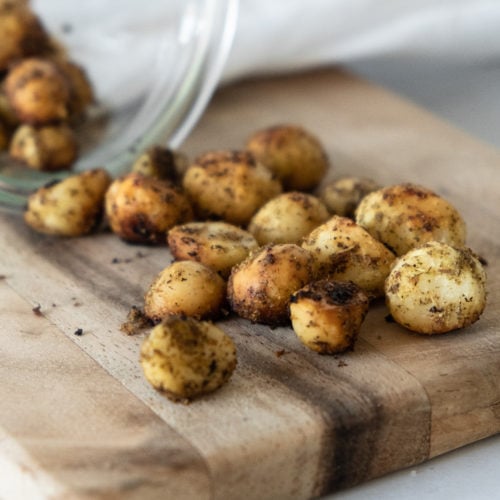Roasted macadamias with lemon myrtle and mountain pepperberry on a wooden board. The golden nuts are lightly dusted with Girri Girri (lemon myrtle) and Mourau (mountain pepperberry), showcasing their rustic texture and vibrant seasoning. A celebration of Indigenous botanicals, artisan craft, and connection to Country by Chocolate On Purpose® — 100% Indigenous-owned, ethically sourced. Perfect for gifting or mindful snacking