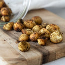 Roasted macadamias with lemon myrtle and mountain pepperberry on a wooden board. The golden nuts are lightly dusted with Girri Girri (lemon myrtle) and Mourau (mountain pepperberry), showcasing their rustic texture and vibrant seasoning. A celebration of Indigenous botanicals, artisan craft, and connection to Country by Chocolate On Purpose® — 100% Indigenous-owned, ethically sourced. Perfect for gifting or mindful snacking
