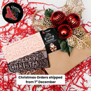 Chocolate On Purpose 'Merry Christmas Gift Hamper Bag' with three chocolate bars, White Chocolate with Ooray (Davidson Plum) and Milk Chocolate with Munthari (Muntrie Berry) and Dark Chocolate with Gulalung (Finger Lime), bag decorated with embellishment of red baubles & gold holly leaves with Babiin Ngungghi (Father of Giving) Gift Tag and Chocolate On Purpose Logo stamp. With message that Christmas Orders shipped from 1st December.