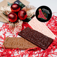 Chocolate On Purpose 'Merry Christmas Gift Hamper Bag' with three chocolate bars, White Chocolate with Ooray (Davidson Plum) and Milk Chocolate with Munthari (Muntrie Berry) and Dark Chocolate with Gulalung (Finger Lime), bag decorated with embellishment of red baubles & gold holly leaves with Chocolate On Purpose Logo stamp.