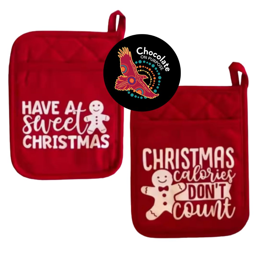 Red quilted pot holders with white festive text, "Have a Sweet Christmas" and "Christmas Calories Don't Count", gingerbread man designs, red hanging loop, Chocolate On Purpose Christmas chocolate making kit component, heat-resistant fabric, Indigenous-owned ethical gifting