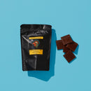 Dark Chocolate Gulalung bag next to pile of chocolate squares
