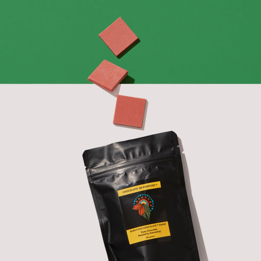 Black bag of Raspberry Ruby Chocolate with 3 pieces above the bag. white and green colorblock background