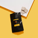 Black bag with WHITE CHOCOLATE WITH ILLAWARRA PLUM (DAALGAAL), 3 pieces of choclate next to bag. yellow and white background